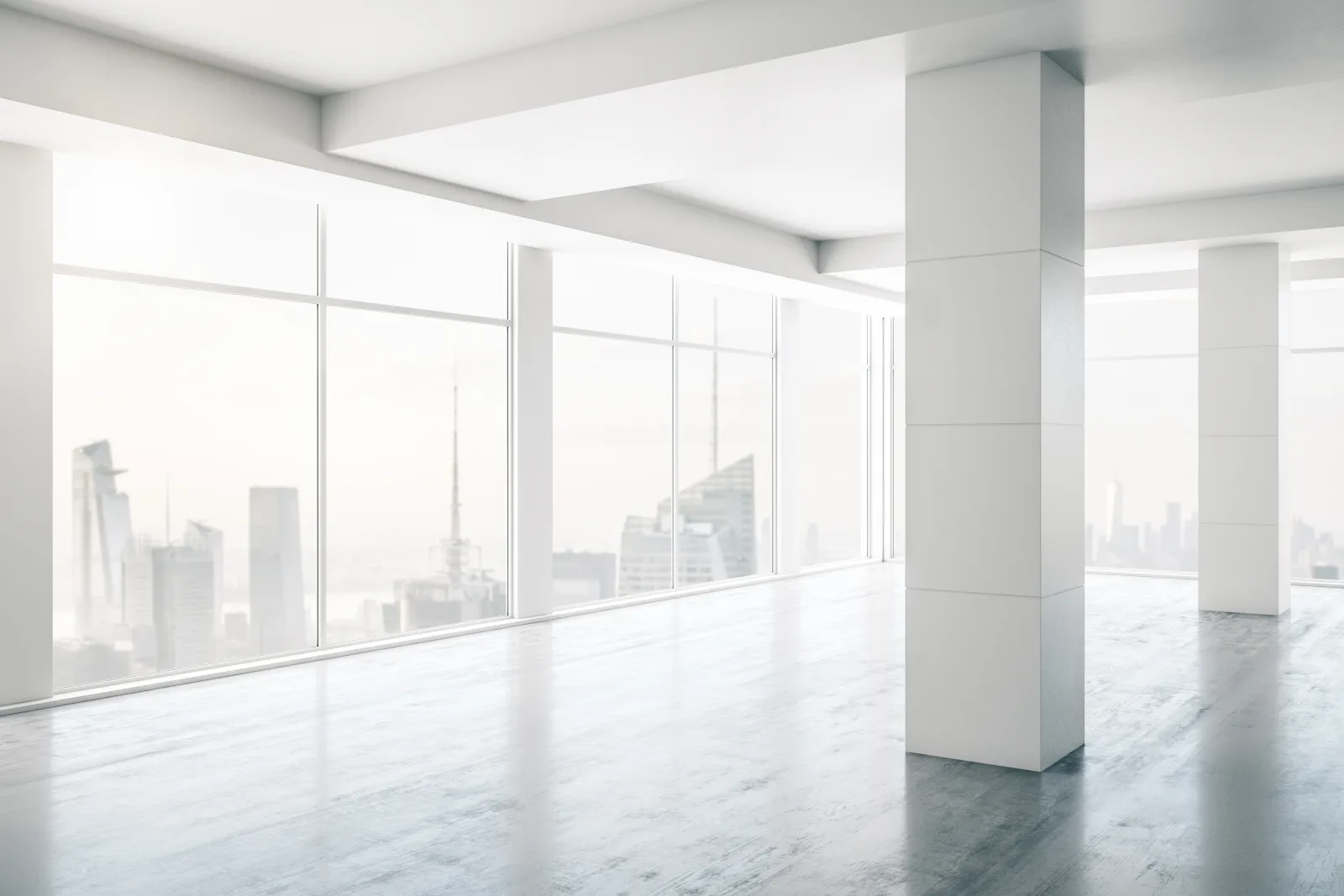 A floor plate handed over as shell — columns, polished slab and full-height glazing onto the skyline.